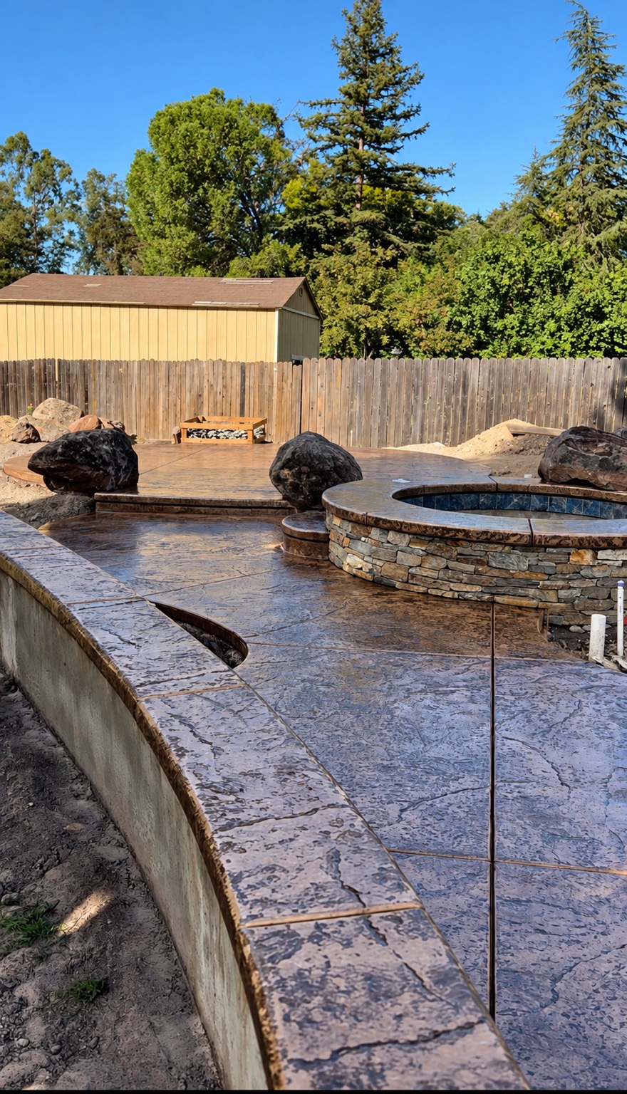 Stamped concrete patio with raised stone spa and curved pool edge